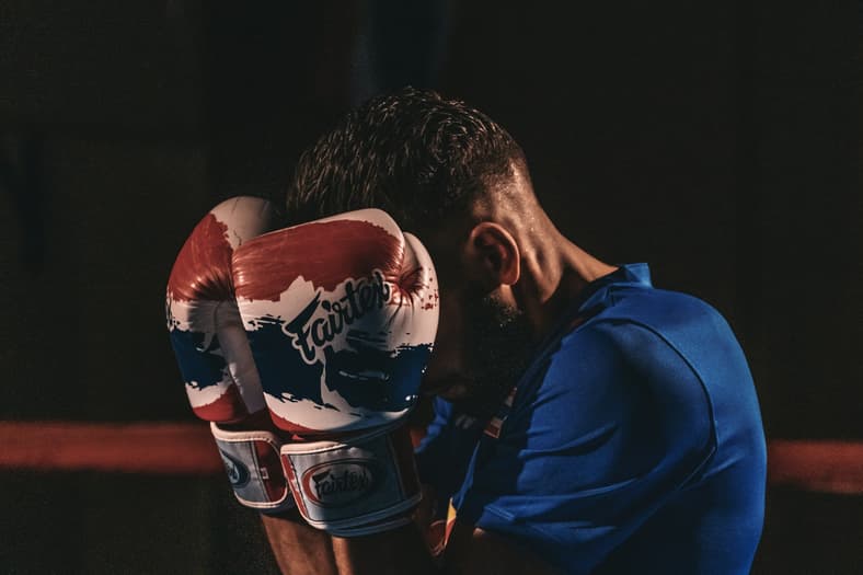 man shielding face with boxing gloves